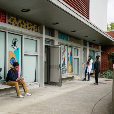 Colourful mural by Sandeep Johal on Surrey Arts Centre classroom windows, with 3 people nearby.