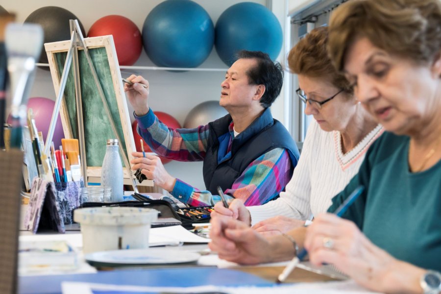 Three seniors painting canvases.